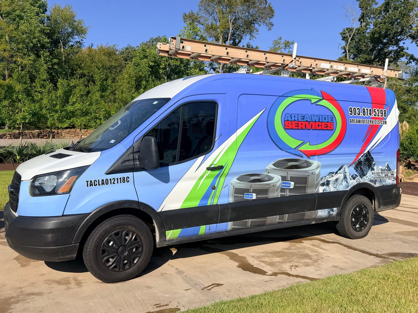 An Area Wide Services van wrapped in the company logo, with a ladder on the roof rack