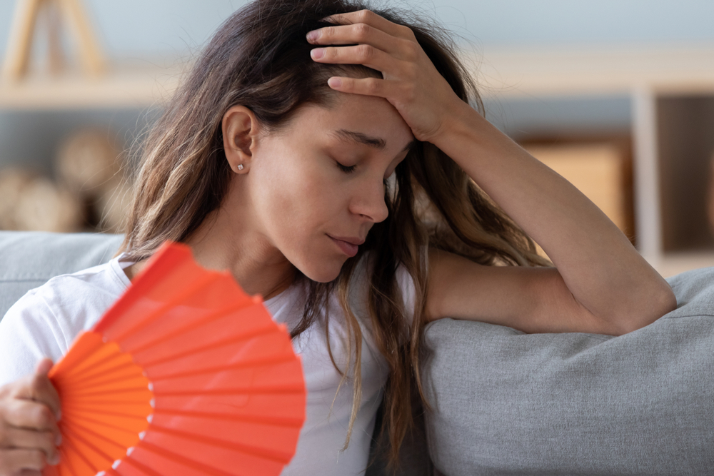 Young Woman Uses a Fan Waiting for AC Repair Services
